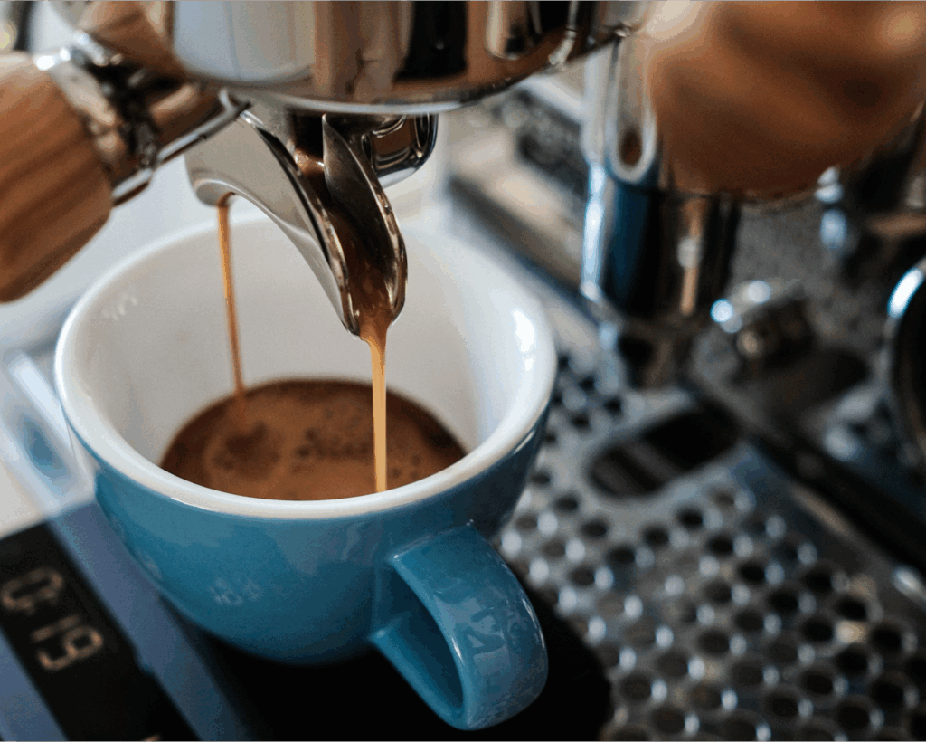 Extracción de café desde portafiltro sobre taza azul de 200ml y está sobre balanza digital para espresso